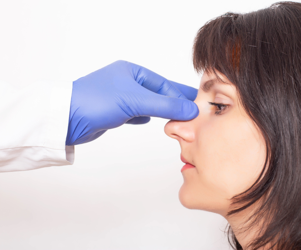 Side profile of a patient having her nose assessed by her plastic surgeon before a rhinoplasty. Side profile of a patient having her nose assessed by her plastic surgeon before a rhinoplasty.